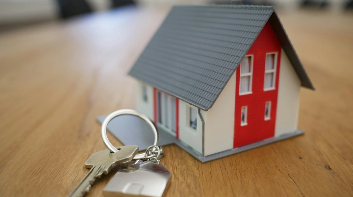 Model house with a set of keys on a wooden table.